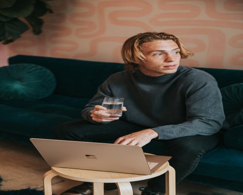 Professional working on a laptop with a glass of water nearby